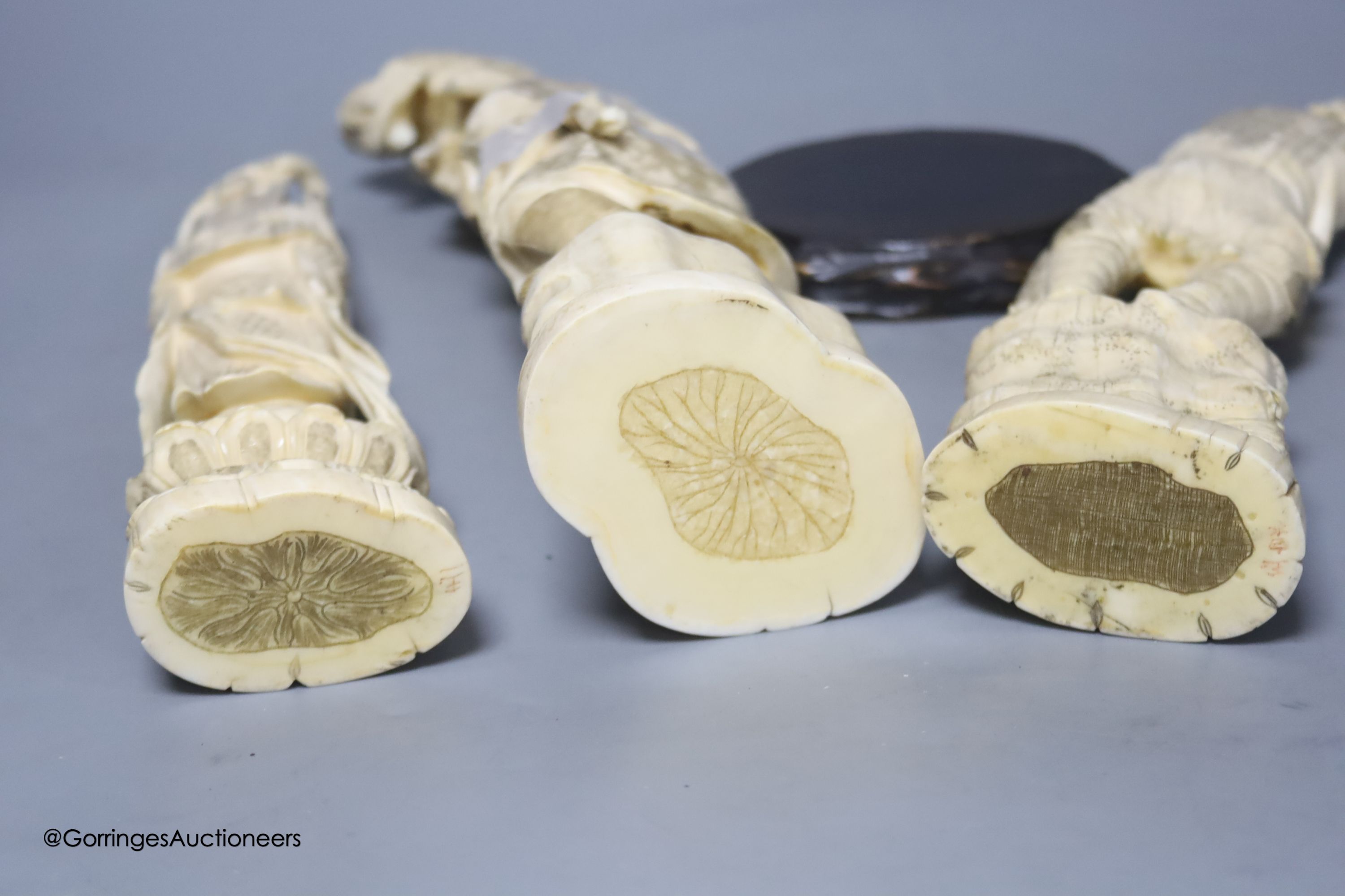 Three Japanese carved walrus ivory okimono, early 20th century, tallest 32cm including wood stand